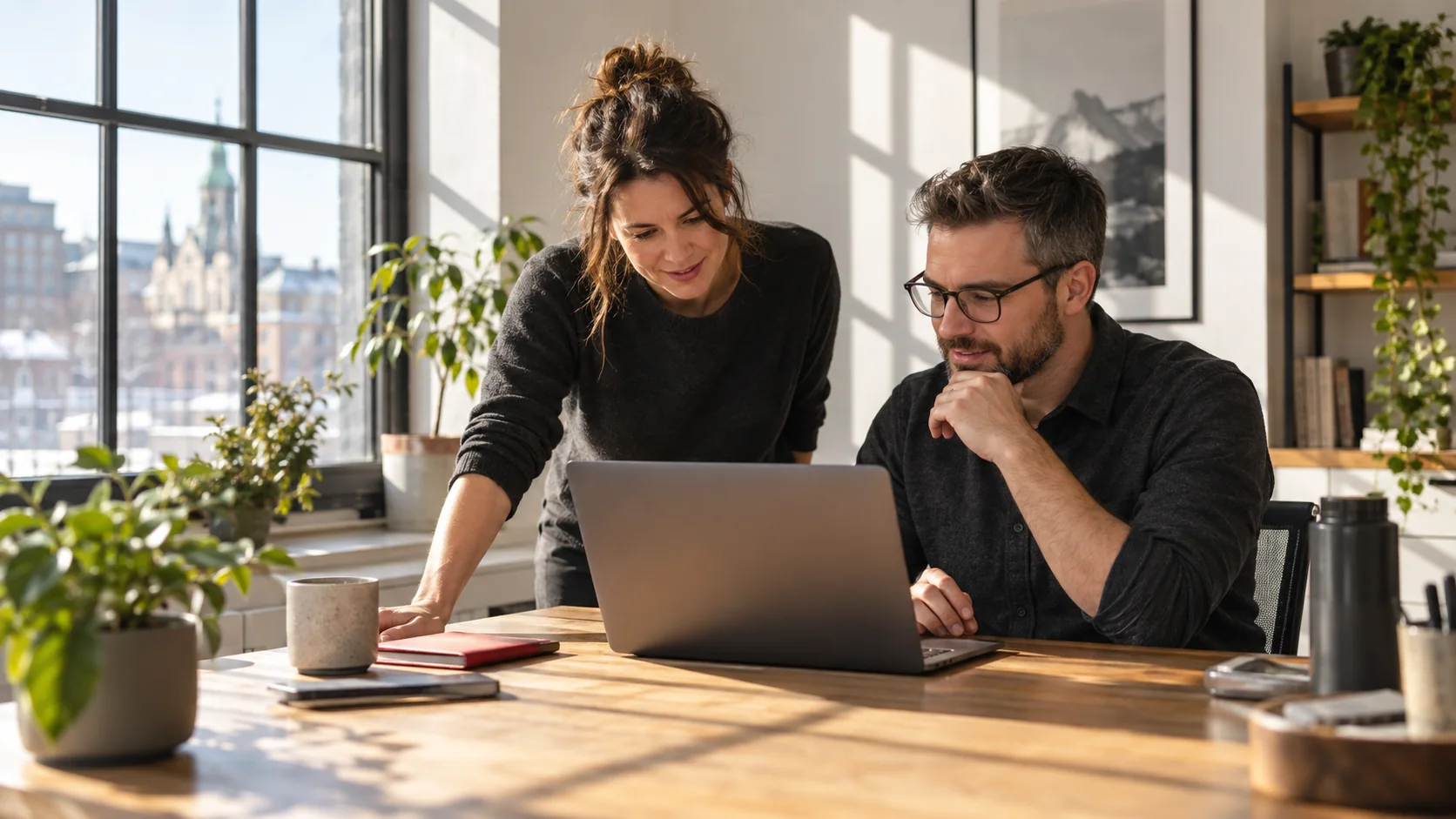 Deux collègues discutent devant un ordinateur dans un bureau lumineux